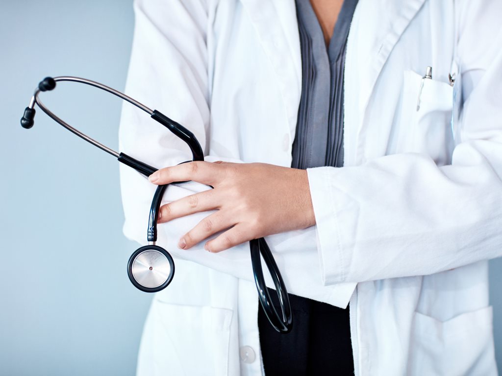 Studio shot of a confident doctor against a blue background holding a stethoscope.