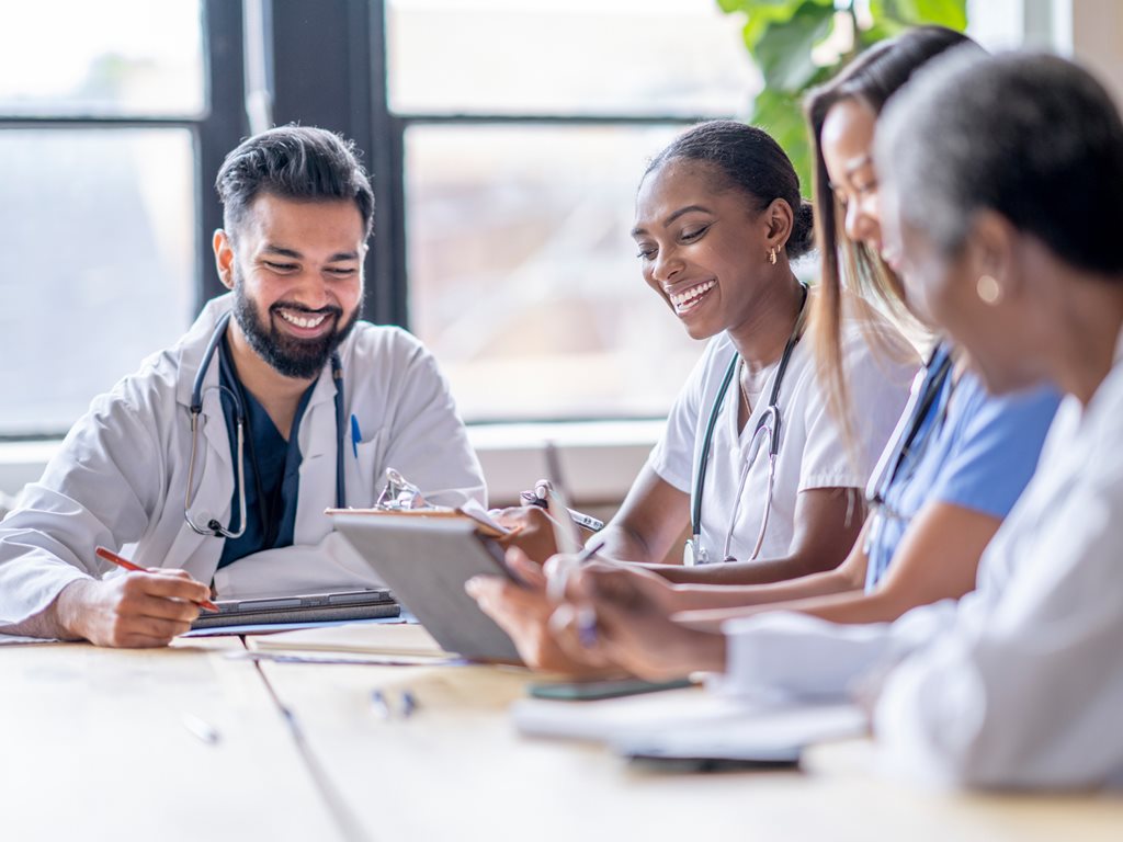 A small group of four medical professionals sit around a table.