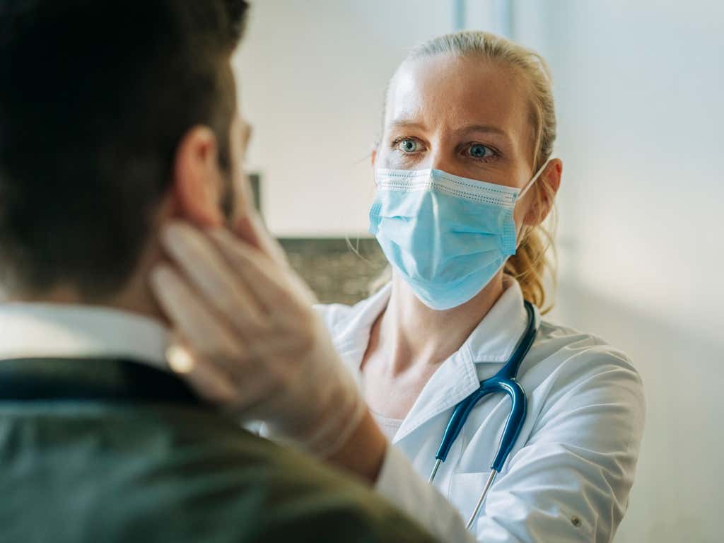 Female doctor wearing surgical mask examining patient.