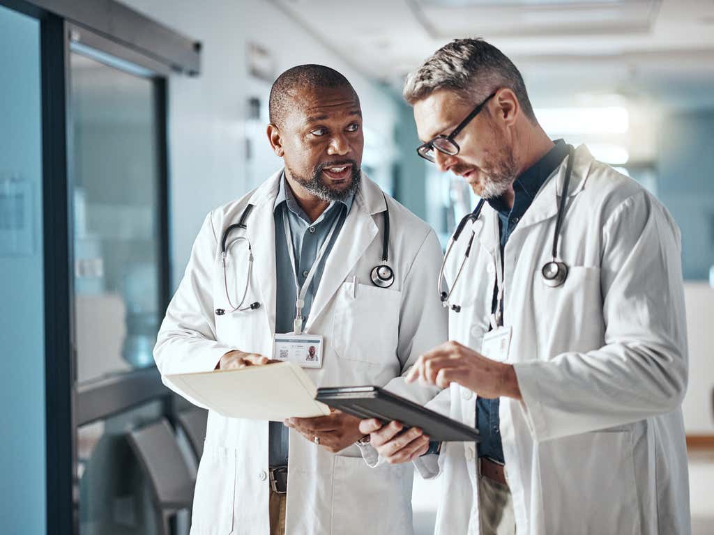 Two doctors talking to each other in a hospital hallway.