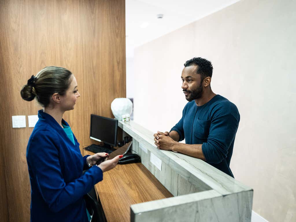 Receptionist talking to a patient at a medical clinic.