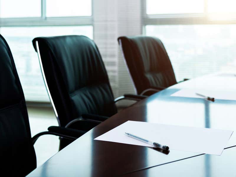 Board room with papers and pens on the table.