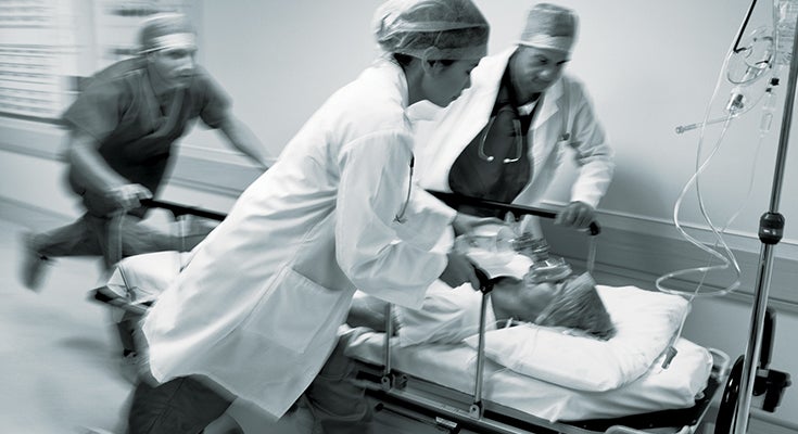Physician working on patient, while rushing through a hallway