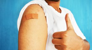 A close-up someone's bandaged arm, giving a thumbs up