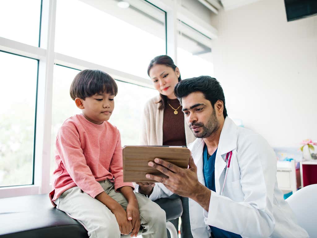 Physician assistant sitting with young boy and his mother in the doctors office.