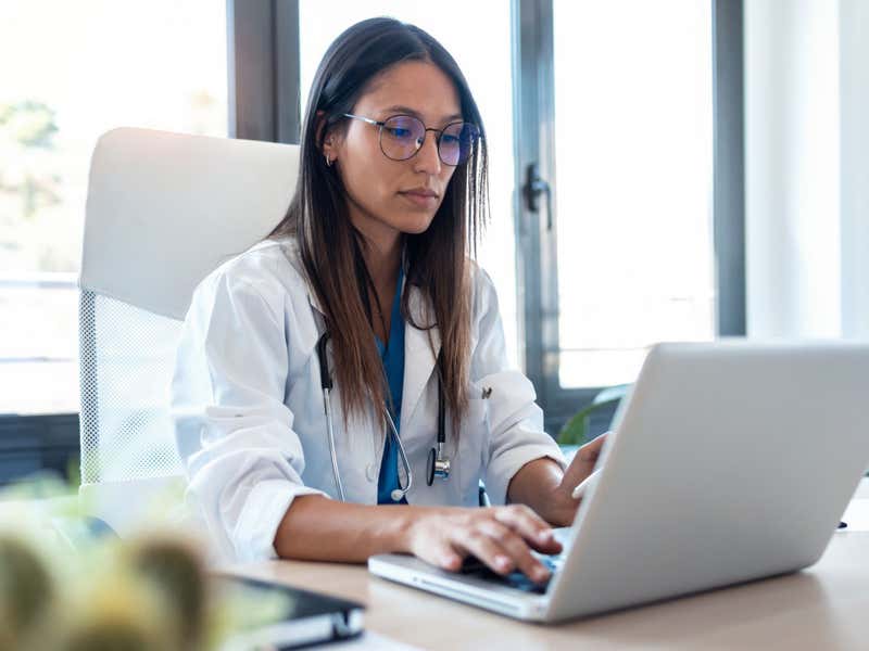Young female doctor in her office working on a laptop.