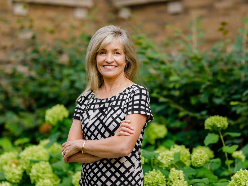 Portrait of Nancy Whitmore with greenery in the background.