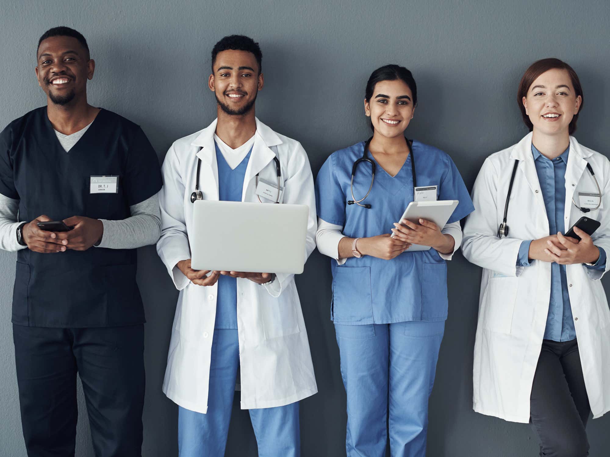 A group of doctors standing against a grey background.