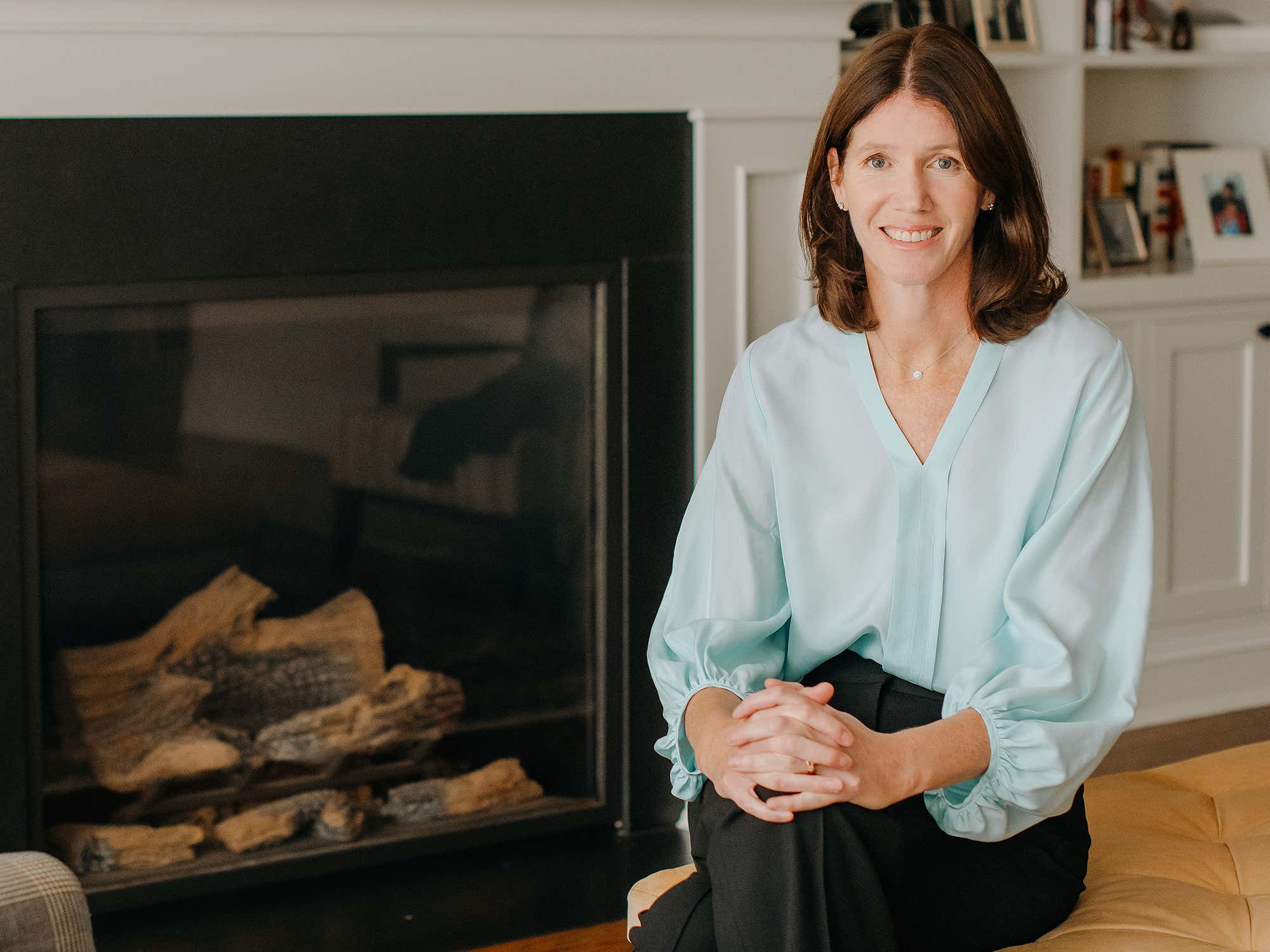 Dr. Sarah Reid sitting in front of a fireplace.