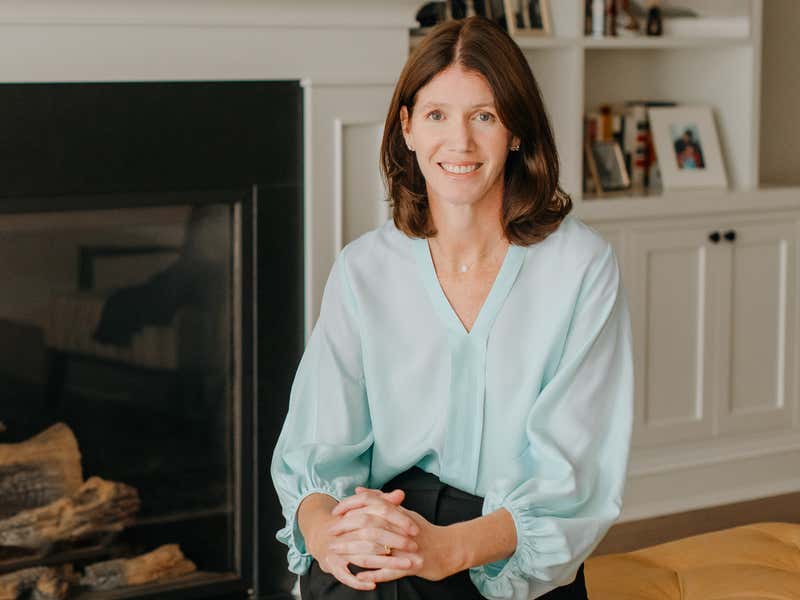 Dr. Sarah Reid sitting in front of a fireplace.