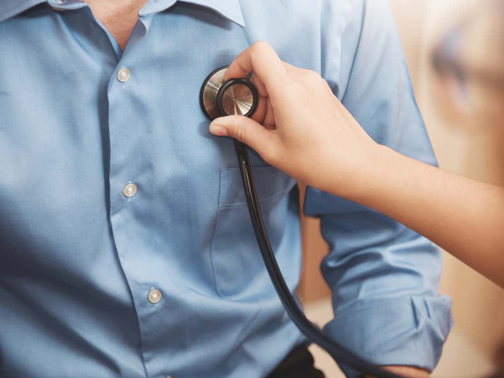 Close up shot of doctor holding a stethoscope to patient's chest.