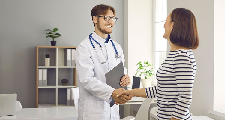 Male health professional greeting and shaking hands with older woman