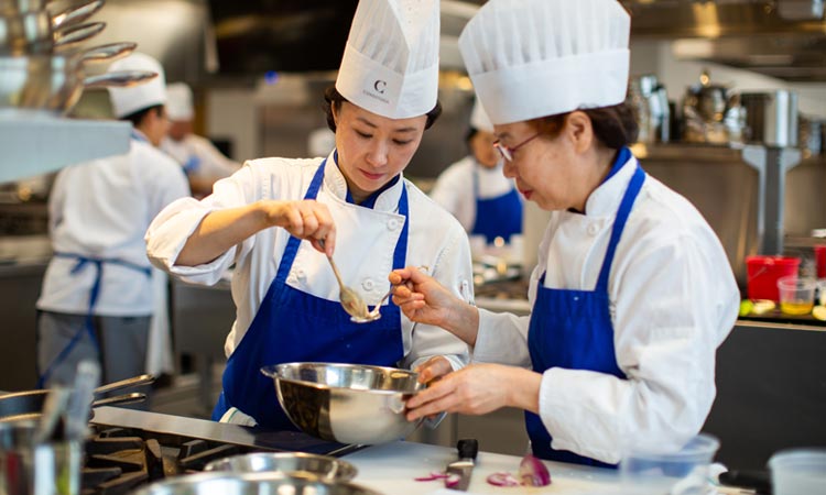 Two chefs preparing ingredients in a professional kitchen.