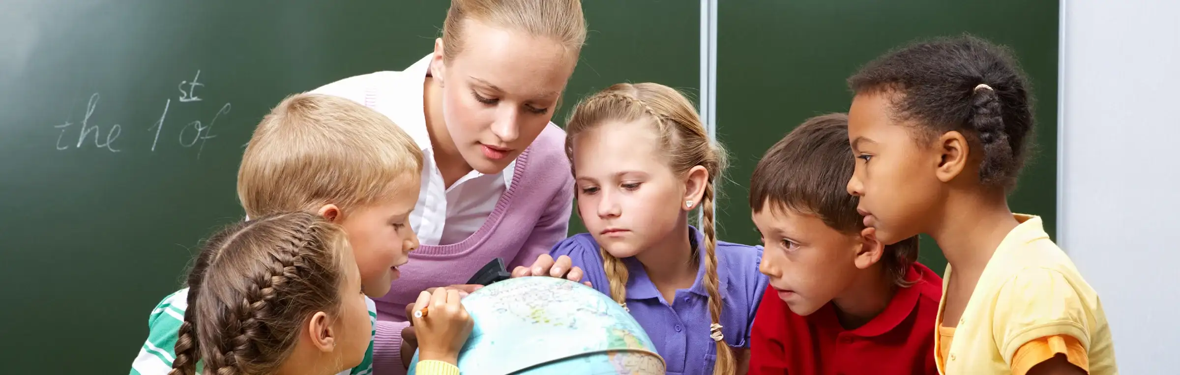 Photo of a teacher showing a diverse group of students a globe.
