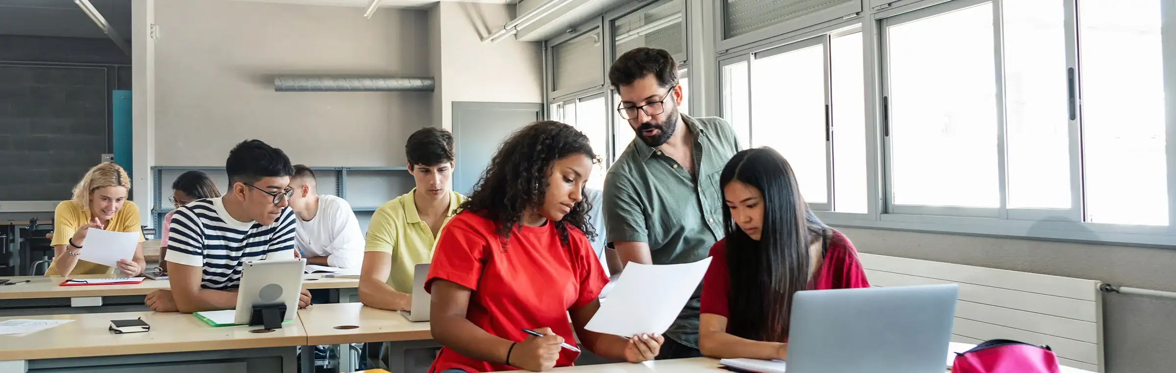 Photo of a teacher checking two students work.