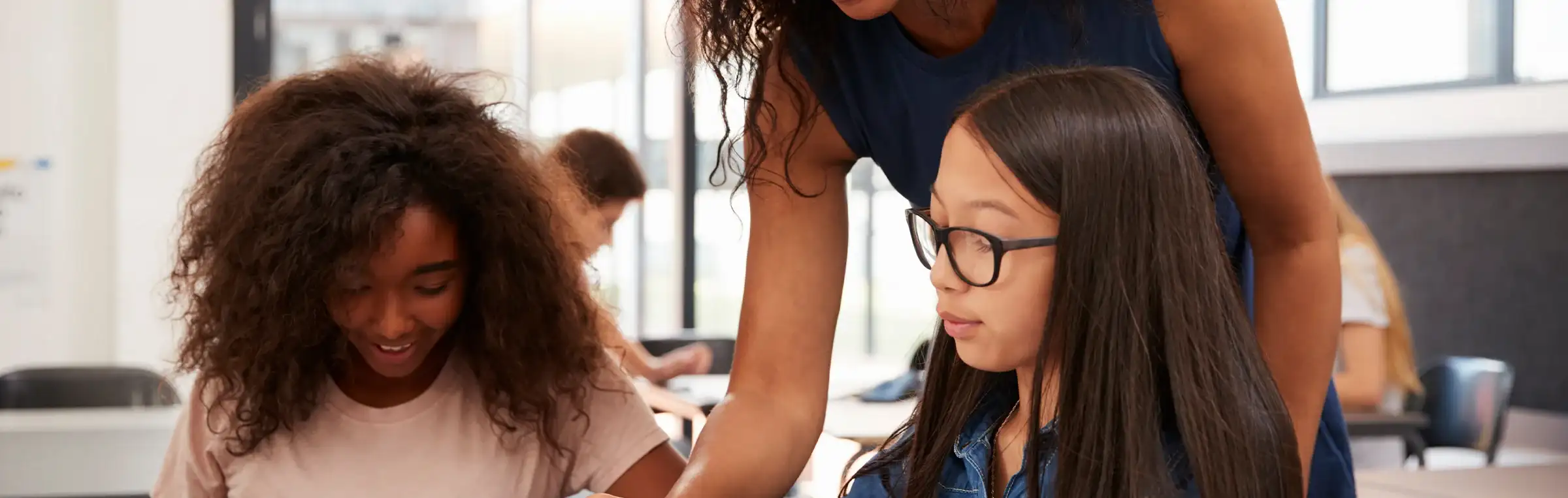 Photo of a teacher engaging with two students.